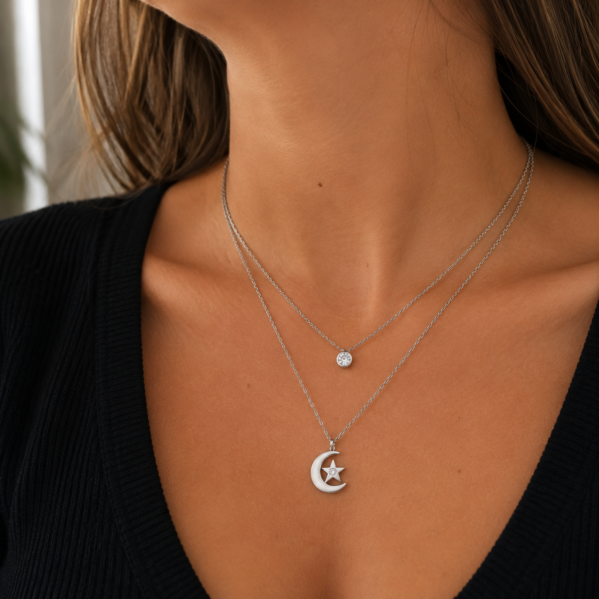 Close-up of a woman wearing the Celestial Whisper silver-tone stainless steel layered moon and star necklace with a black V-neck top.