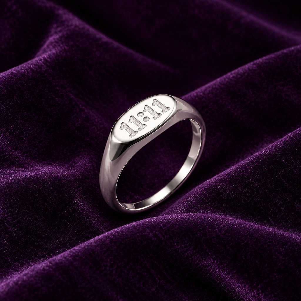 Silver finish stainless steel Divine Timing 11:11 ring displayed on deep purple velvet