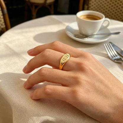 Gold stainless steel Divine Timing 11:11 Ring worn on a woman's hand, resting on a cream tablecloth beside a cup of coffee.