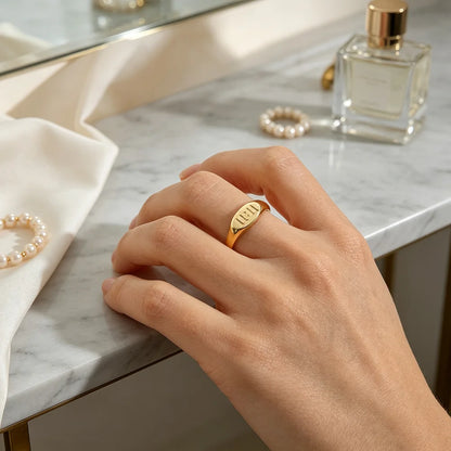 Gold stainless steel Divine Timing 11:11 Ring worn on a woman's hand beside a marble dressing table with perfume and pearl jewellery.