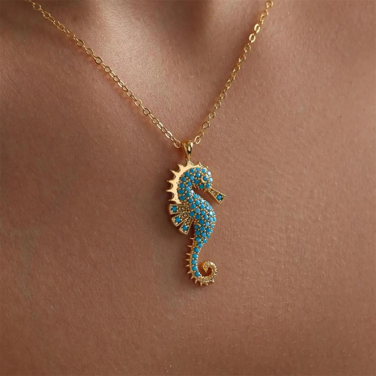 Close-up of Ocean's Guardian Seahorse Necklace worn around the neck, featuring an 18K gold-plated stainless steel pendant with turquoise-coloured zircon stones.