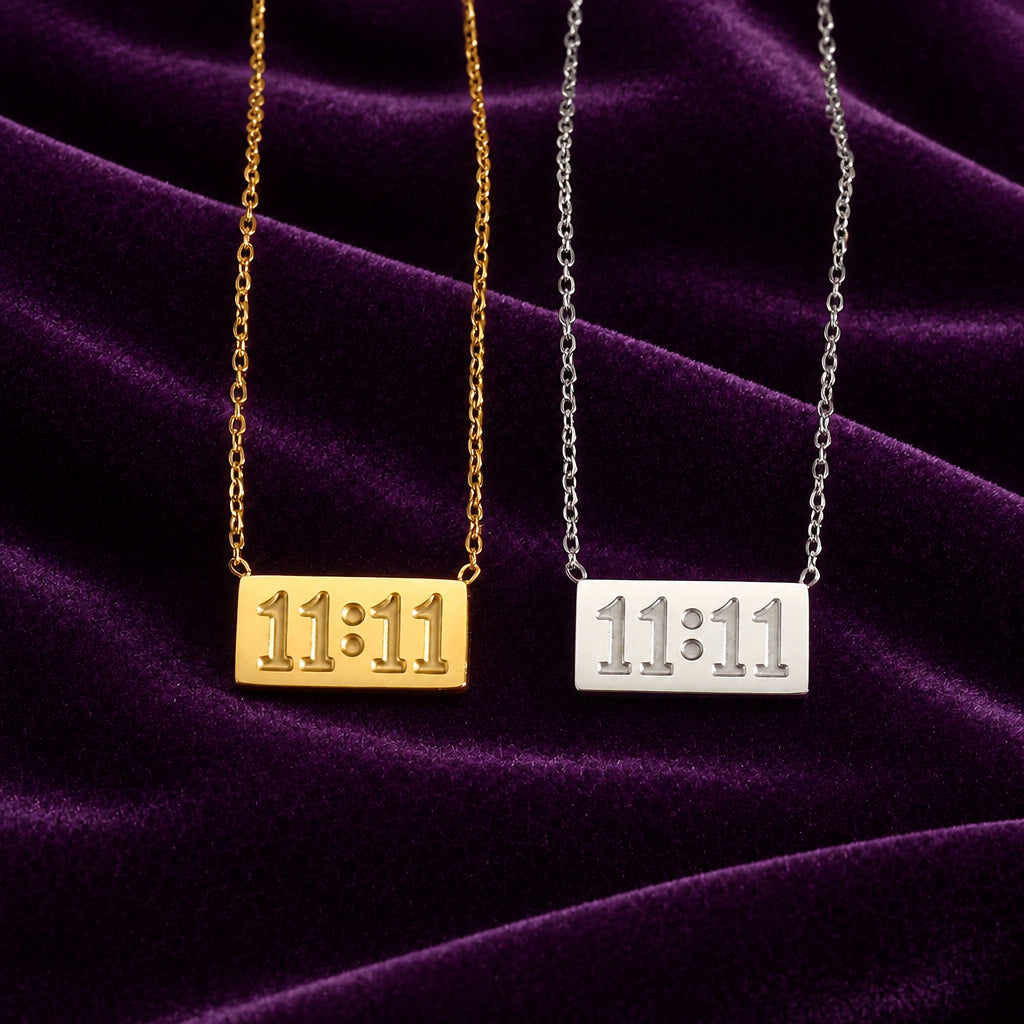 Divine Timing 11:11 stainless steel pendant necklaces in gold and silver, displayed side by side on luxurious purple velvet fabric.